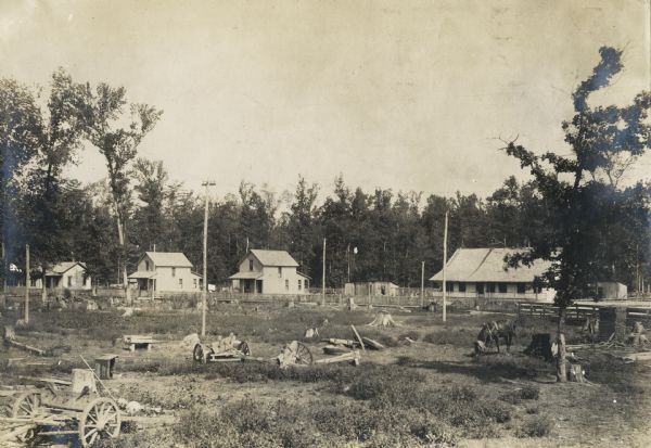 Buildings at a logging camp or sawmill operated by the International Harvester Company. A horse is in the right foreground.