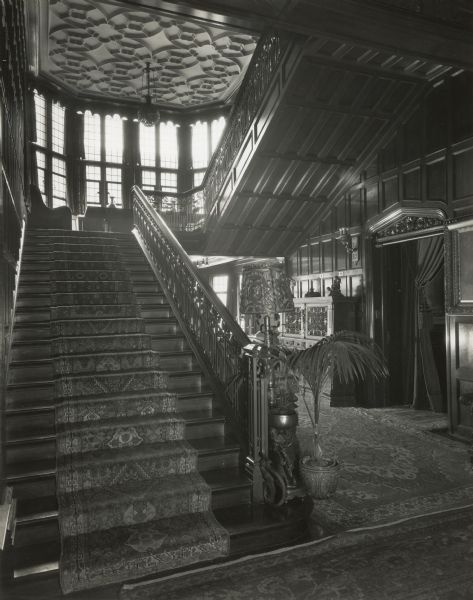 Stairway from the main hall to the second floor at Cyrus McCormick,Jr.'s residence at 50 East Huron Street, with a view of the house's east windows. The door to the Empire Room is at right. Although they can barely be seen in the picture, writing on the back of the photograph identifies the painting at the extreme right of the photograph as that of Cyrus H. McCormick (the 1st), and the rug hanging on the wall at the top of the stairs at the far left of the photograph as a "valuable Sepahan prayer rug."