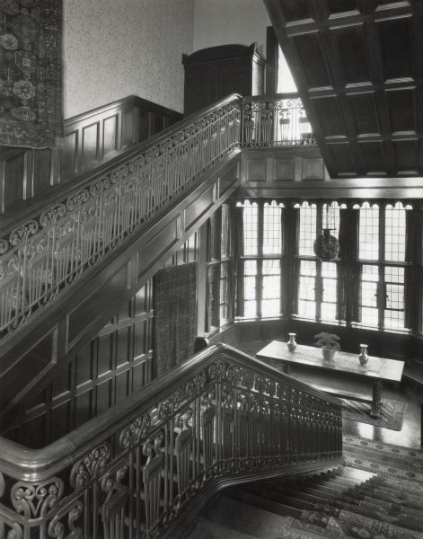 Main stairway of Cyrus McCormick, Jr.'s residence at 50 East Huron Street. This view is of the section of stairway from the first landing to the second landing, in front of the house's east windows. According to original caption, a "Sepahan prayer rug" hangs on the wall in the lower left of the image.