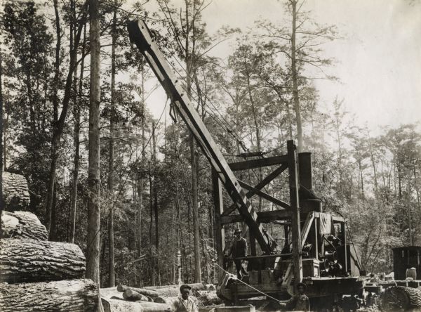 Men using a large crane at an International Harvester logging operation.