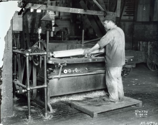 Factory worker placing a piece of wood into a machine at International Harvester's McCormick Works.