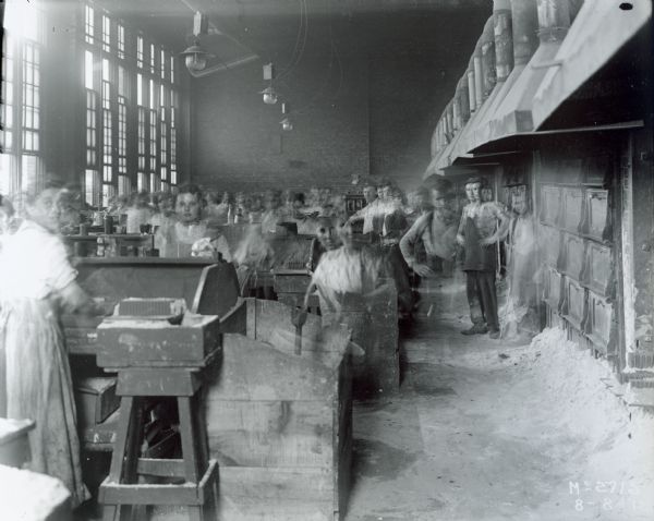 Male and female factory workers (blurred by motion) at International Harvester's McCormick Works.