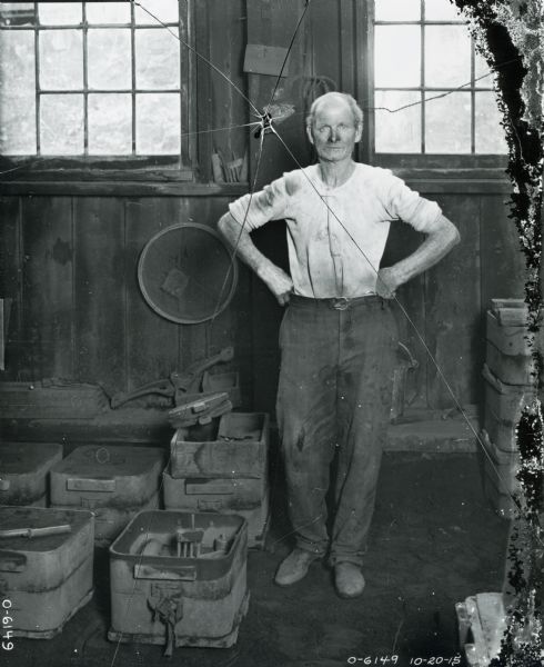 An Osborne Works factory worker(?) standing in a workshop or storage facility.