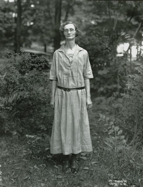 A female factory worker(?) from Osborne Works posing for a portrait in a wooded area.