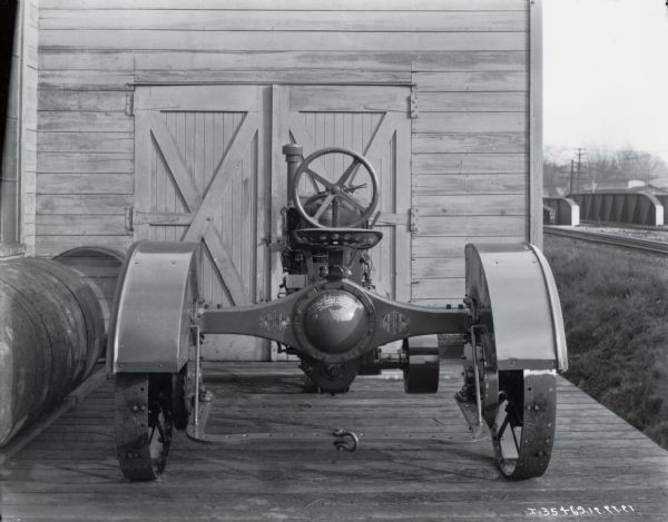 Rear view of a Farmall Regular tractor on a wooden platform, possibly near an International Harvester factory.