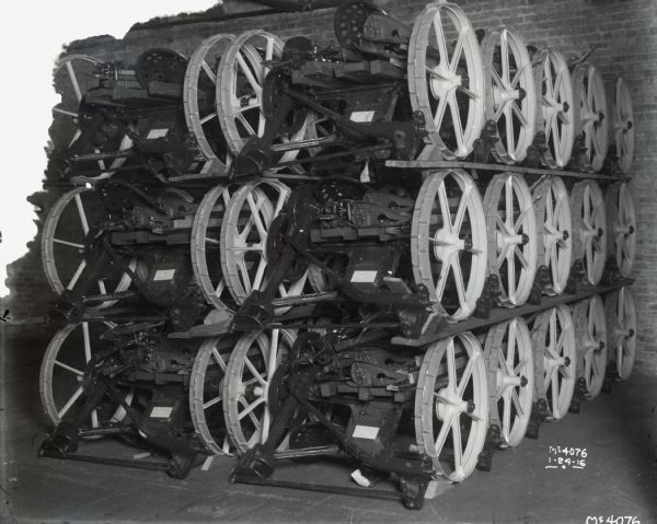 Two rows of fifteen sickle bar mowers(?) stacked at an International Harvester factory (most likely McCormick Works in Chicago).