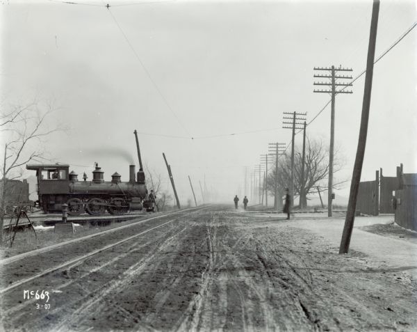 The engine of a train stopped at a crossroad, possibly near International Harvester's McCormick Works (factory).