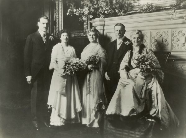 Cyrus McCormick III (1890-1970), his fiancée Dorothy Linn (b. 1892), his mother Harriet Hammond McCormick (1862-1921), his father Cyrus McCormick Jr. (1859-1936), and his grandmother Nettie Fowler McCormick (1835-1923) at a ball given for Cyrus III and Dorothy. The men wear formal suits, and the women wear long dresses and carry bouquets of flowers.