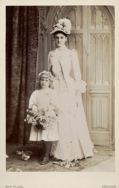 Full-length carte-de-visite of Anita McCormick Blaine (1866-1954) dressed as a bridesmaid for the wedding of her brother Cyrus McCormick, Jr. (1859-1936) to Harriet Hammond (1862-1921). Elizabeth Morse is the flower girl.
