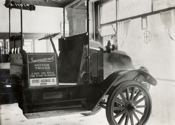 A sign for International Motor Trucks reading "A Size and Style for Every Business" rests on a truck at Deport Hardware Co. The store may have been located in Deport, Texas.