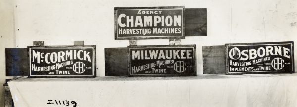 A series of four International Harvester advertising signs, including: McCormick Harvesting Machines and Twine; Agency Champion Harvesting Machines; Milwaukee Harvesting Machines and Twine; and Osborne Harvesting Machines, Implements and Twine.