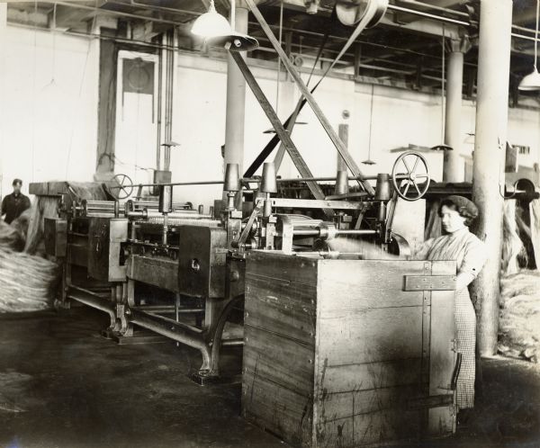 A young woman works at her station in a factory - probably the Deering Twine Mill.