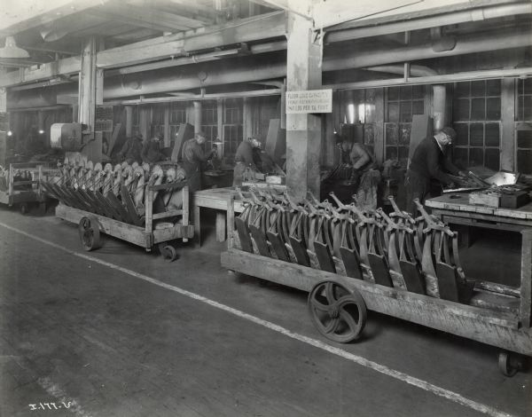 Factory workers and long wheeled carts filled with implement parts at the Chattanooga Plow Works.