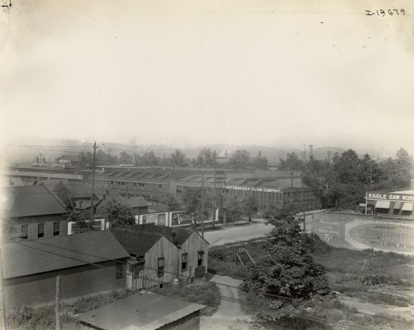 Elevated view of the Chattanooga Plow Works. The Eagle Saw Works building is on the right in the background. There are billboards along a street in the center. Lettering on the large building in the center reads "Chattanooga Plow Company." The photograph was likely taken around the time of the sale of the company to International Harvester. After the sale, the factory became known as the "Chattanooga Plow Works."