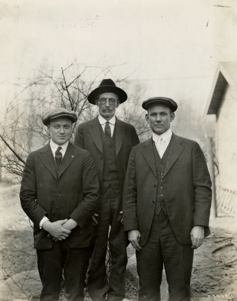 Mr. S.E. Burns, an International Harvester dealer, poses for a portrait with his son and son-in-law on either side of him.