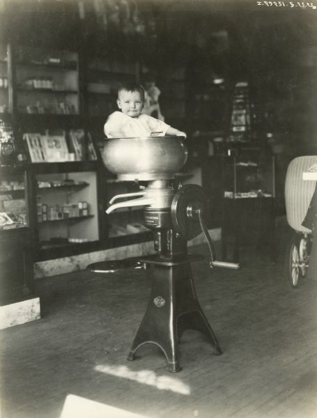One-year-old Bernard Hicks poses for a photograph in a Primrose cream separator in a store or dealership.