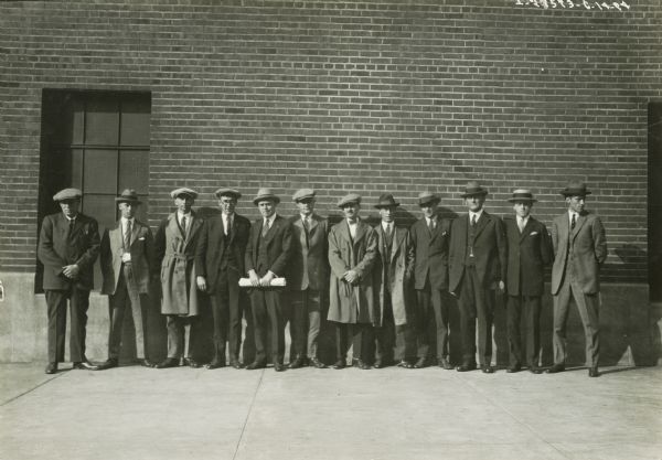 A group of International Harvester "advertising men" line up in front of a building.