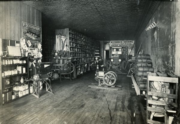 Interior view of the Comanche Implement Company, an International Harvester dealership. A stationary engine is on the floor.