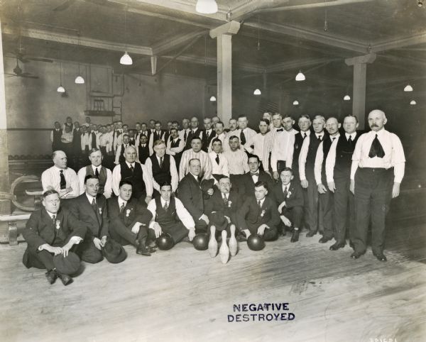 Men, possibly International Harvester employees, posing for a group portrait with bowling balls and pins.