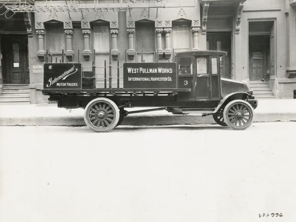 International Model "L-101" truck parked alongside a curb. The truck has a sign advertising the company's West Pullman Works.