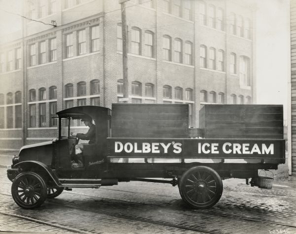 A driver sits behind the wheel of an International Model "L-101" truck used by Dolbey's Ice Cream.