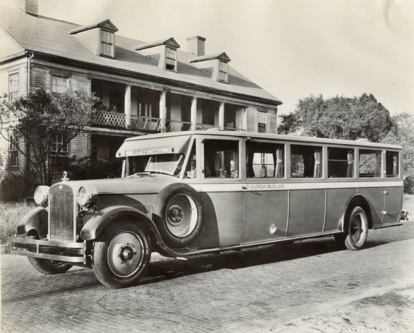 An International bus, model 52 or model 53, parked in front of a two-story wood frame building, possibly a boarding house. The side of the coach has "Florida Blue Line" written on it, and the front panel of the car says "Special."
