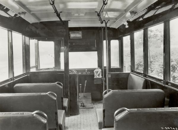 The interior, looking forward, of an International Harvester bus, or motor coach. The interior features large windows, corner-handled seats and a wide center aisle. The bus was built on a model 52 or model 53 chassis.