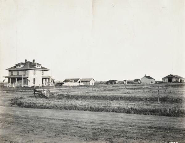 Farmhouse and outbuildings in the distance. A road is in the foreground.