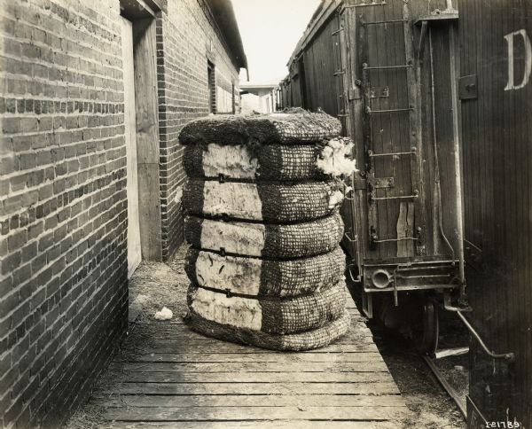 A cotton bale sits on a platform next to a train, possibly awaiting shipment.