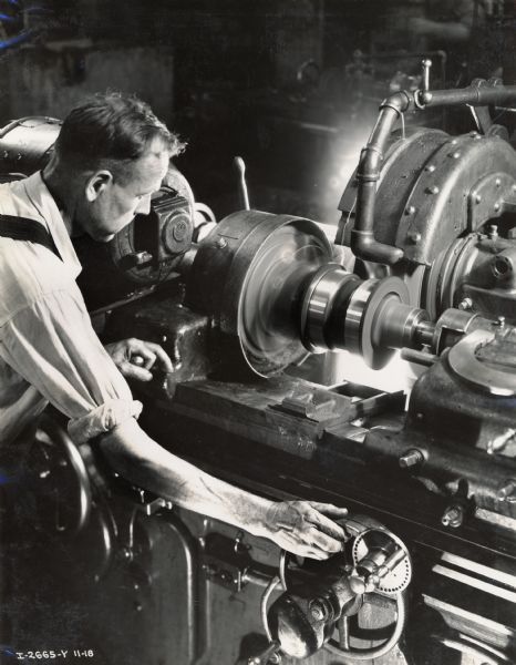Factory worker grinding an external tractor track roller shell at Milwaukee Works.