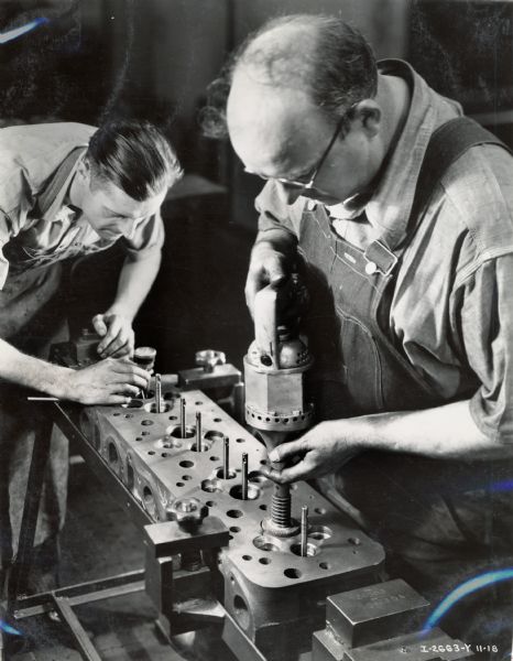 Two factory workers drill and grind valve slats into a diesel engine at Milwaukee Works. Photograph taken by Don Jones.