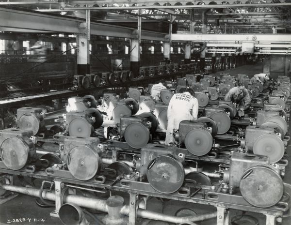 A group of "service managers" inspect engines at Milwaukee Works (factory). Photograph taken by McQuinn.