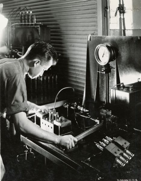 Factory worker tests a diesel engine pump under 6000 pounds of pressure at Milwaukee Works. Photograph taken by Don Jones.