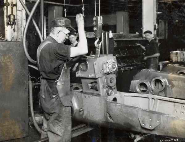 Factory worker installs a transmission in a W-30 tractor on an assembly line at Milwaukee Works.