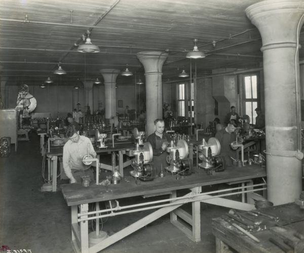 Factory workers at their stations on long tables at Milwaukee Works.