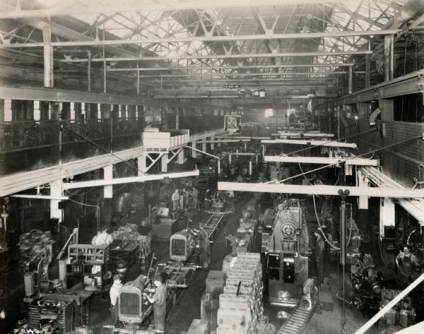 Elevated view of a tractor assembly line at Milwaukee Works, including factory workers and machines.