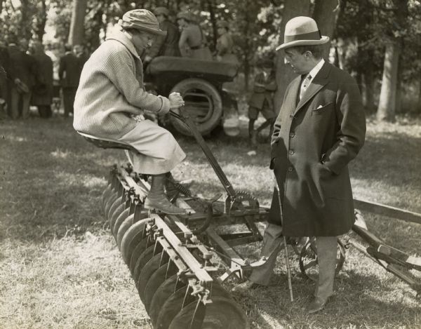 Florence(?) Ward sits on disk harrow or plow at Liberty Farm as J. Ogden Armour looks on.