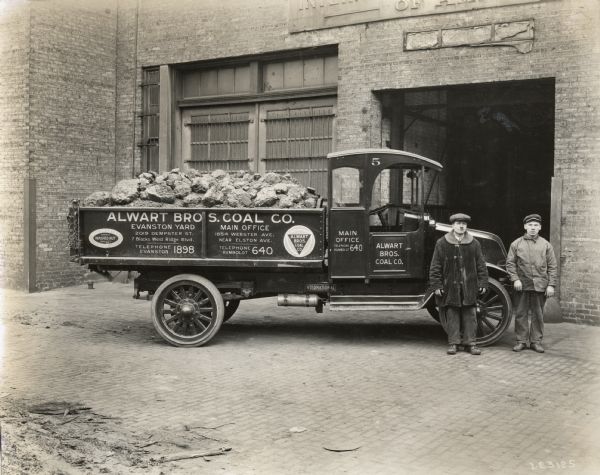 Two men standing in front of their International G-61 truck. The truck was operated by Alwart Brother's Coal Company of Chicago and Evanston. An advertisement on the truck reads "Pocahontas Coal: Highest Washed Nut Quality."