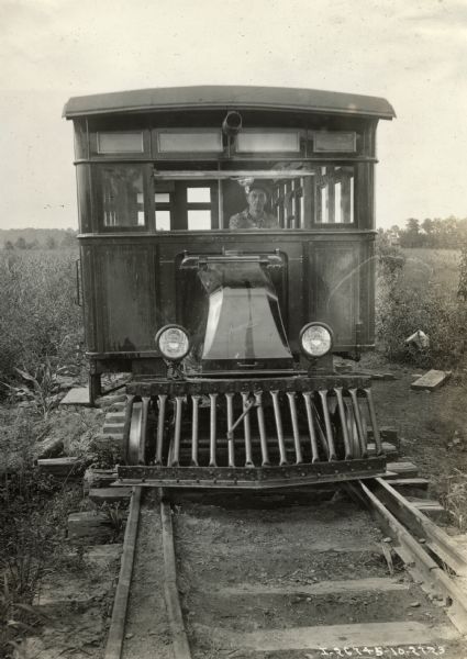 A driver sits in an International Model G or 61 truck fitted with railway gears and wheels for the Ozark-Southern Railway Company.