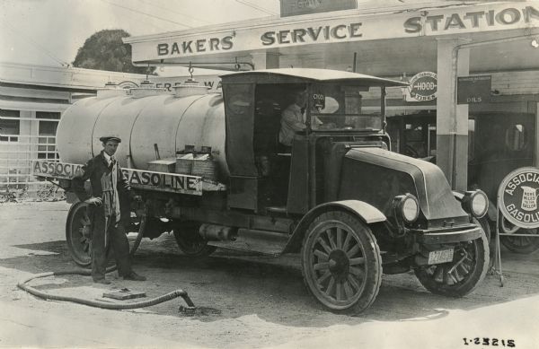 A man fills up an International Model G or 61 truck for the Associated Gasoline Company at Bakers' Service Station.