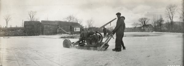 A man uses an International 6 H.P. stationary engine and sawcutter to cut through ice. The caption beneath with the photograph reads: "Ice used by our dealer, H.N. Myers & Son."