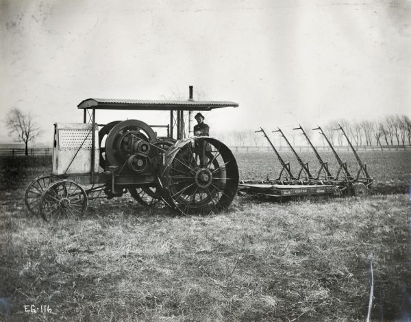 A man pulls an Oliver plow with an International tractor in a foggy field.