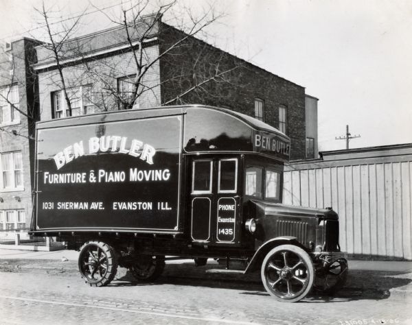 International Model 63 moving truck parked in a residential neighborhood. Text on the side of the truck reads: "Ben Butler Furniture and Piano Moving."
