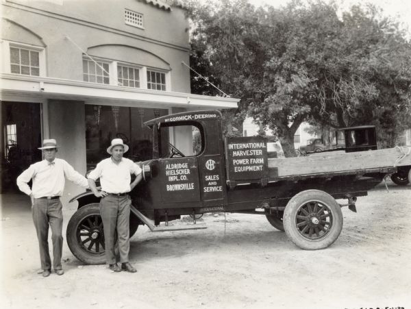 H.C. and W.J. Aldridge stand in front of their International truck. The men operated an International Harvester dealership - the Aldridge Hielscher Implement Company. The dealership building is in the background.