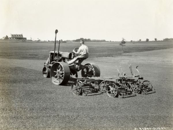 Man using a Farmall Fairway tractor with a mower to tend the golf course of the Aurora Country Club.