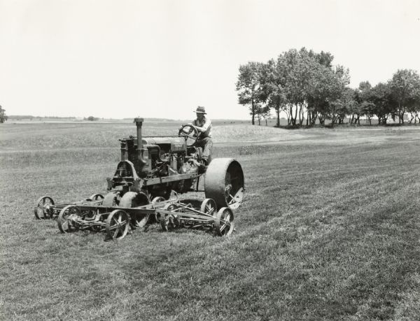 A man uses a McCormick-Deering Fairway tractor with a mowing attachment to cut the grass at Waubonsie Golf Course.