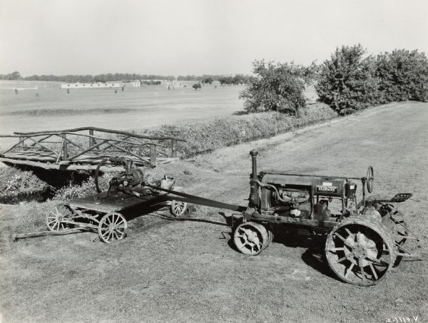 Elevated view of a McCormick-Deering Fairway tractor hooked up to a water pump(?) near a creek at Indian Head Golf Club.