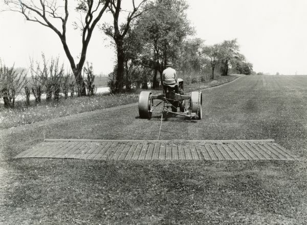 A groundskeeper uses a Fairway tractor to maintain the grounds of what appears to be a golf course.