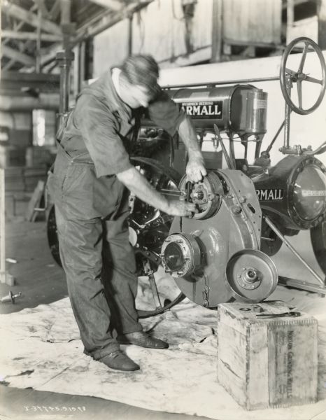 A man is using various tools to overhaul a Farmall Regular tractor.