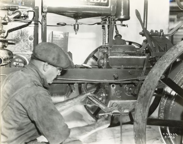 Close-up of a man using tools to overhaul a Farmall Regular tractor.